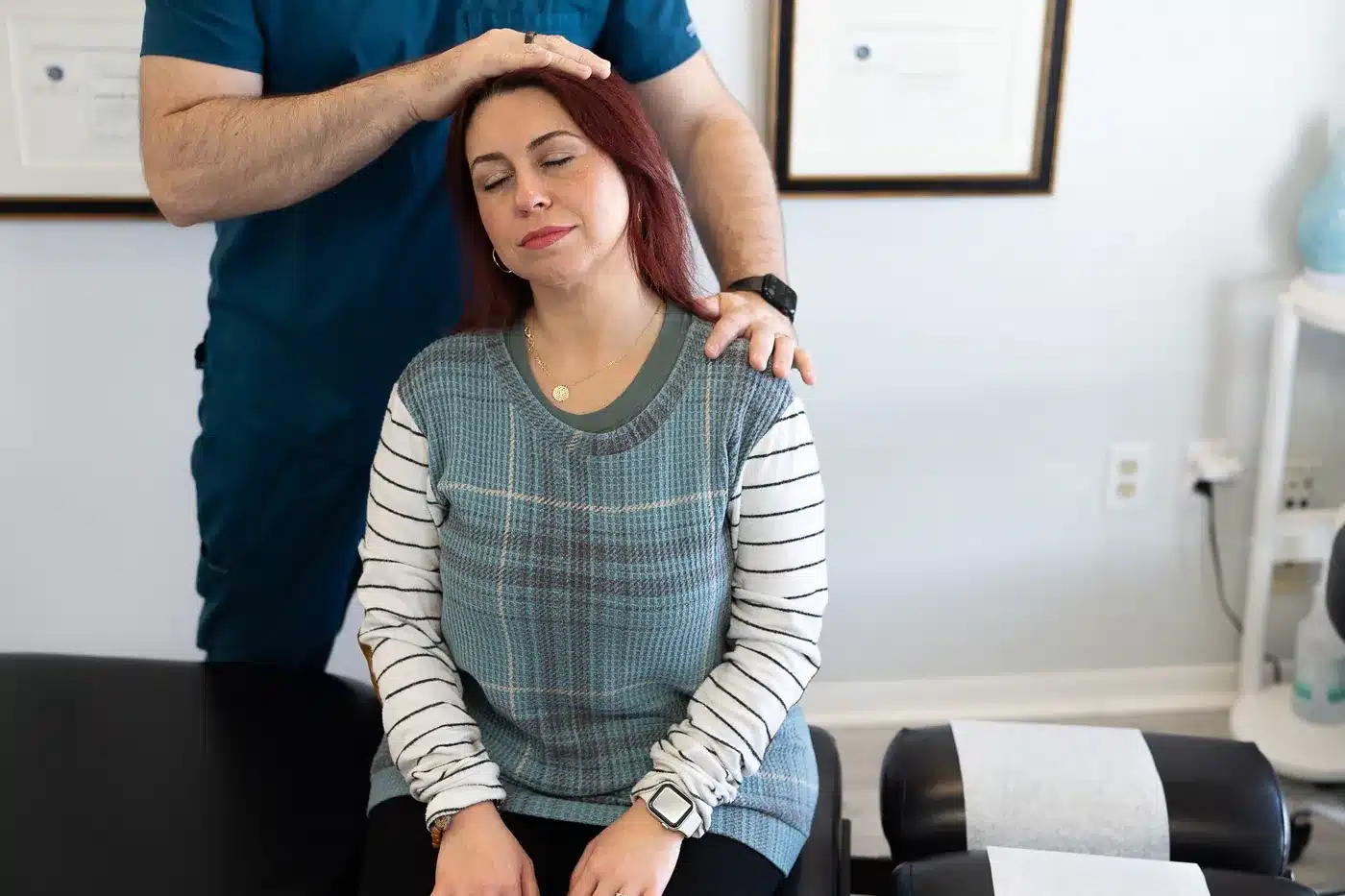Dr. Bobby Koser, DC, chiropractic physician, guiding a seated patient's neck through side bending during a cervical examination at HealthSpine Chiropractic in Carrollwood, Tampa.