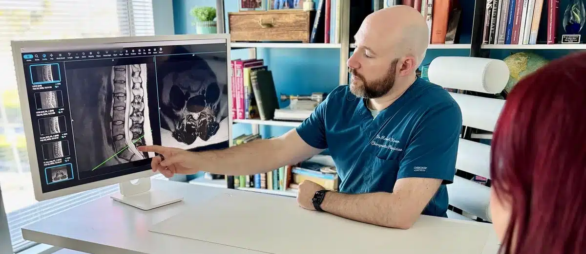 Dr. Bobby Koser, DC, chiropractic physician, pointing out a disc level on a lumbar MRI while going over it with a patient at HealthSpine Chiropractic in Carrollwood, Tampa.