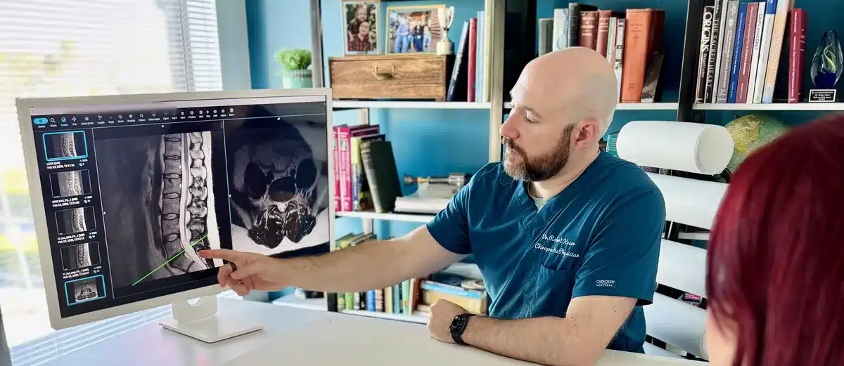 Dr. Bobby Koser, DC, chiropractic physician, reviewing a spinal MRI on screen with a patient at HealthSpine Chiropractic in Carrollwood, Tampa.