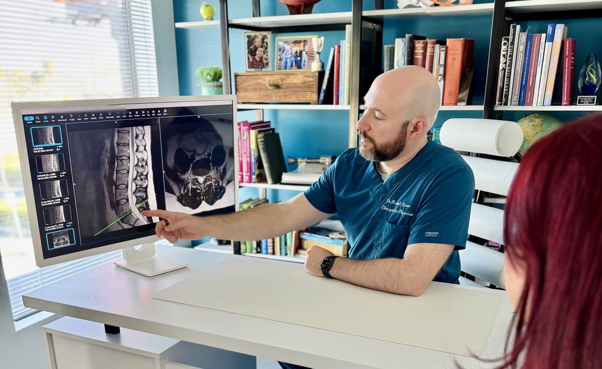 Dr. Bobby Koser, DC, chiropractic physician, reviewing a lumbar MRI on screen with a patient at HealthSpine Chiropractic in Carrollwood, Tampa.