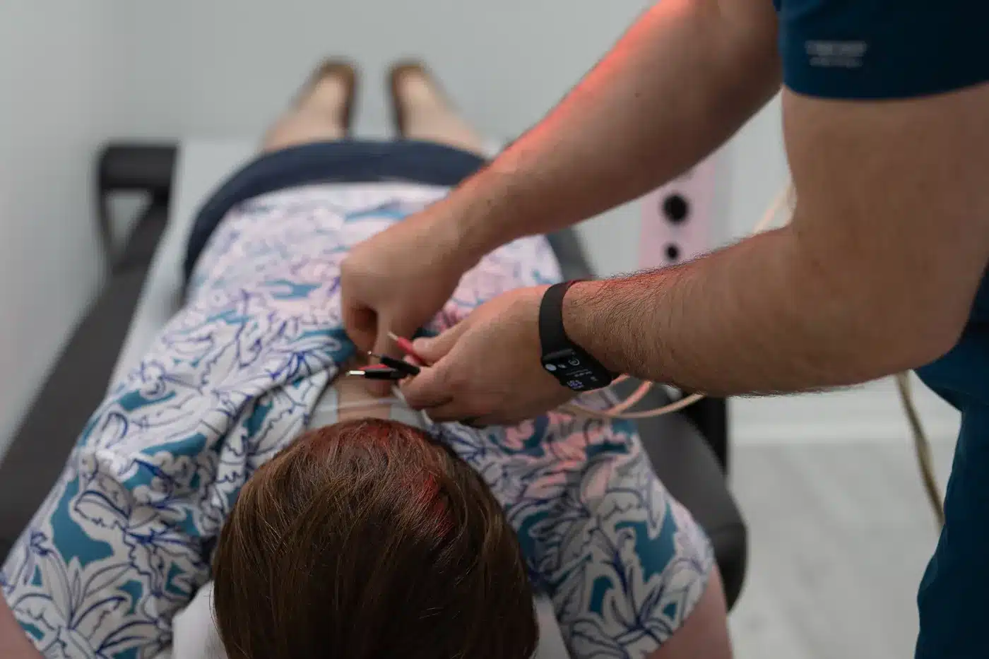 Dr. Bobby Koser, DC, chiropractic physician, attaching electrical stimulation leads to a patient&rsquo;s upper back during a visit at HealthSpine Chiropractic in Carrollwood, Tampa.
