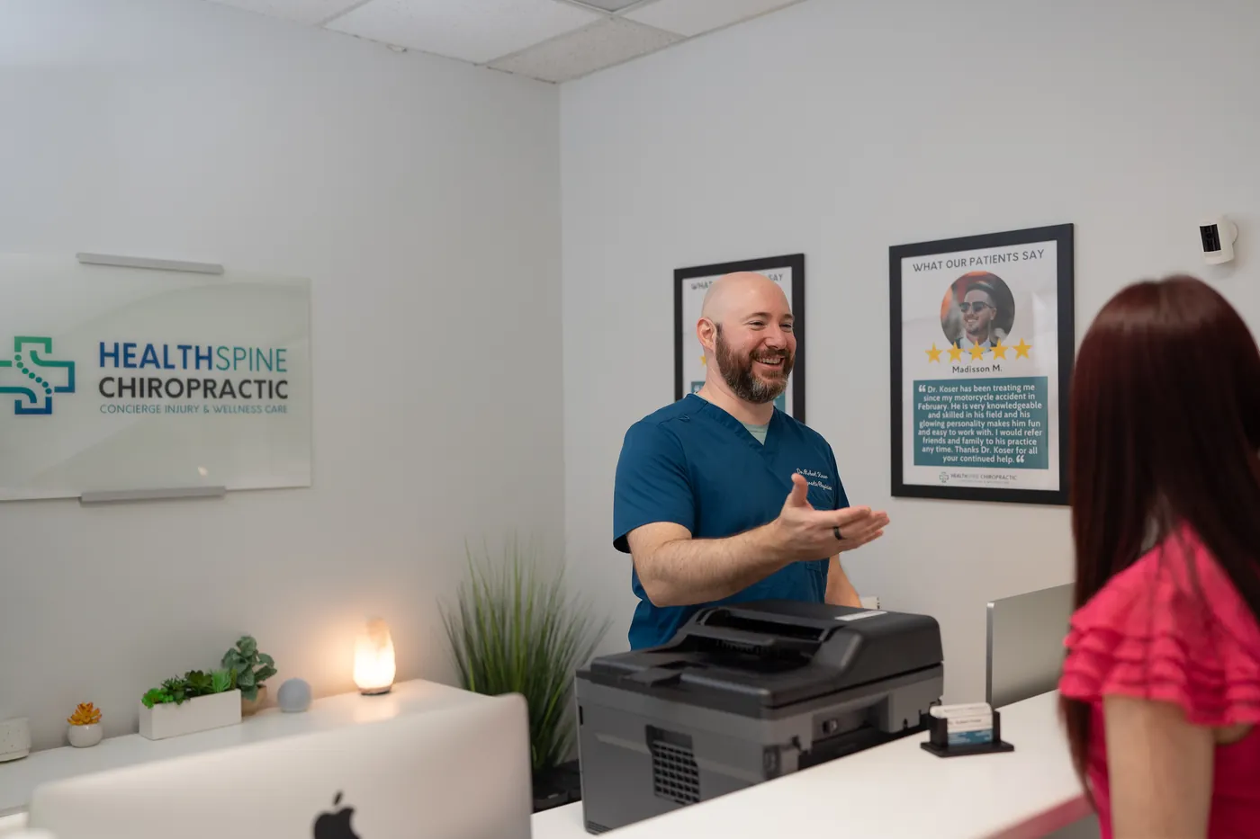 Dr. Bobby Koser, DC, chiropractic physician, welcoming a patient at the check-in desk of HealthSpine Chiropractic on N. Dale Mabry Highway in Carrollwood, Tampa.