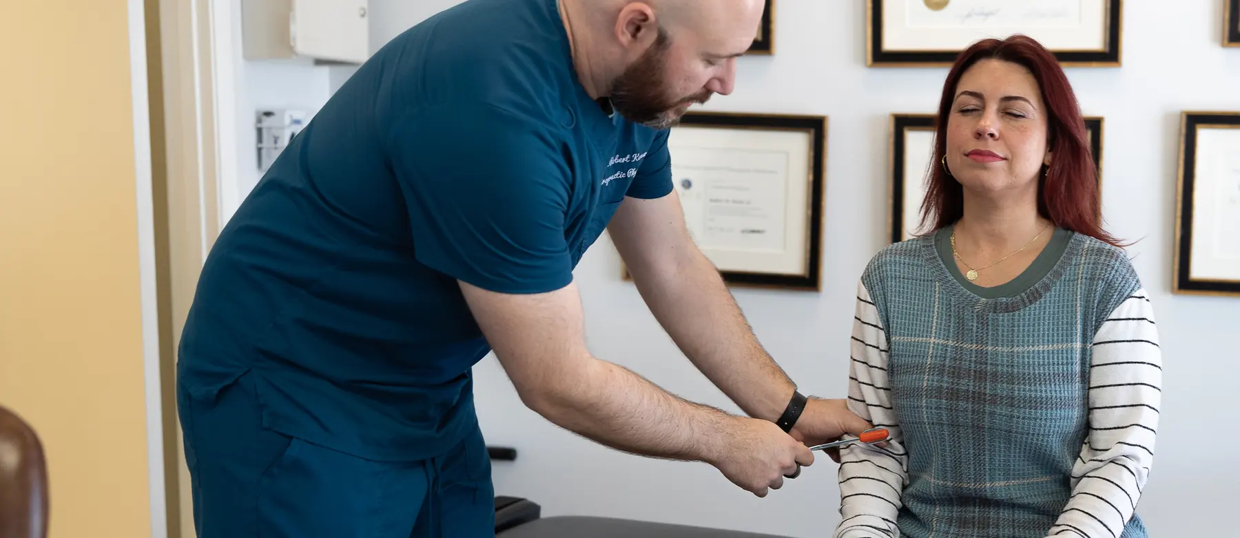 Dr. Bobby Koser, DC, chiropractic physician, testing a seated patient&rsquo;s arm during a neck examination at HealthSpine Chiropractic in Carrollwood, Tampa.