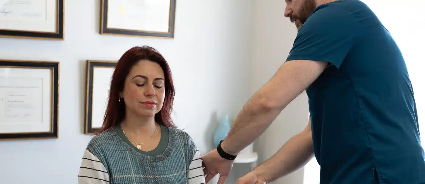 Dr. Bobby Koser, DC, chiropractic physician, assessing a seated patient’s arm during a neurological examination at HealthSpine Chiropractic in Carrollwood, Tampa.