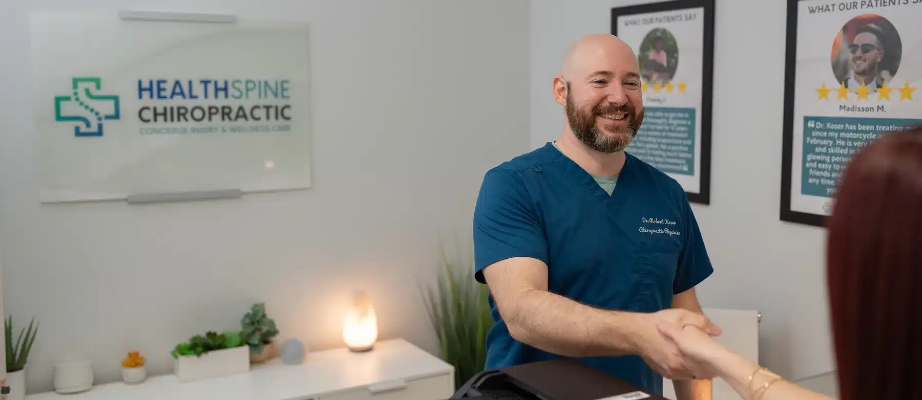 Dr. Bobby Koser, DC, chiropractic physician, welcoming a patient at the front desk of HealthSpine Chiropractic in Carrollwood, Tampa.