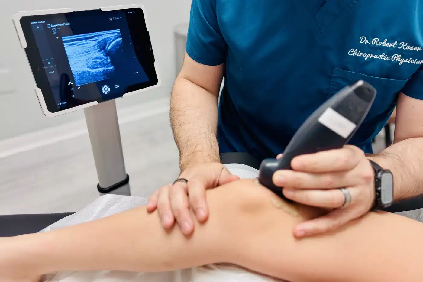 Dr. Bobby Koser, DC, chiropractic physician, scanning a patient's knee with live ultrasound during a Pain Source Exam at HealthSpine Chiropractic in Carrollwood, Tampa.
